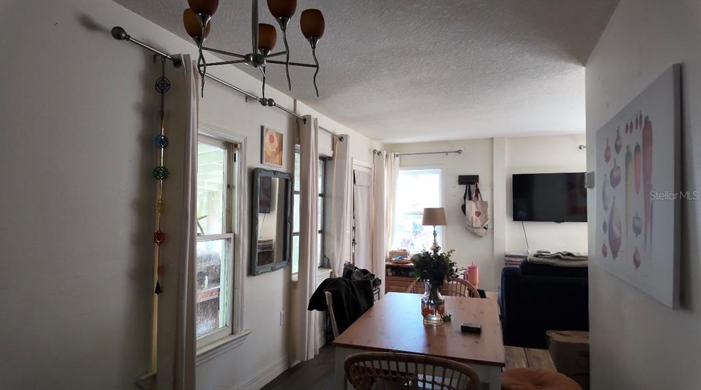 A dining area features a wooden table, a modern chandelier, and windows with white curtains — 1121 ORANGE AVENUE, DUNEDIN, FL