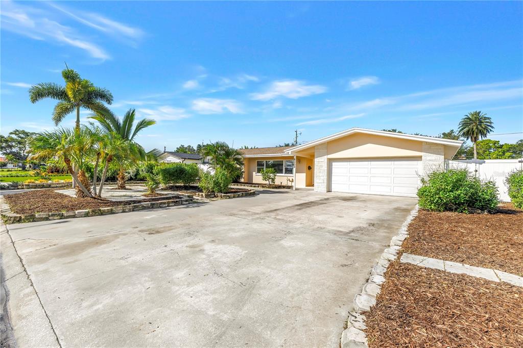 A single-story house with a large concrete driveway, palm trees, and a two-car garage — 2053 DOLPHIN BOULEVARD S, ST PETERSBURG, FL