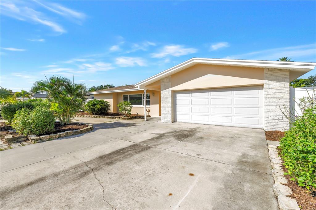 A single-story house with a white garage door, concrete driveway, and landscaped front yard — 2053 DOLPHIN BOULEVARD S, ST PETERSBURG, FL