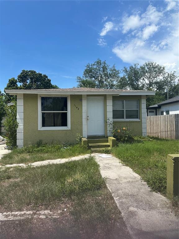 A single-story house with green stucco walls, white trim, and a concrete walkway — 1142 ENGMAN STREET, CLEARWATER, FL