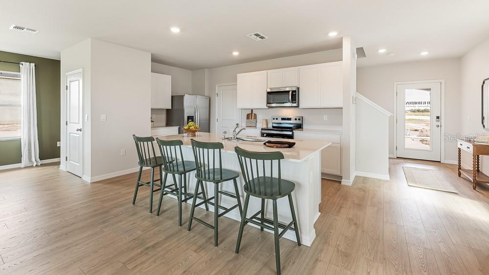 A kitchen features white cabinets, a central island with four green chairs, and light flooring — 1733 COBB TRAIL, PARRISH, FL