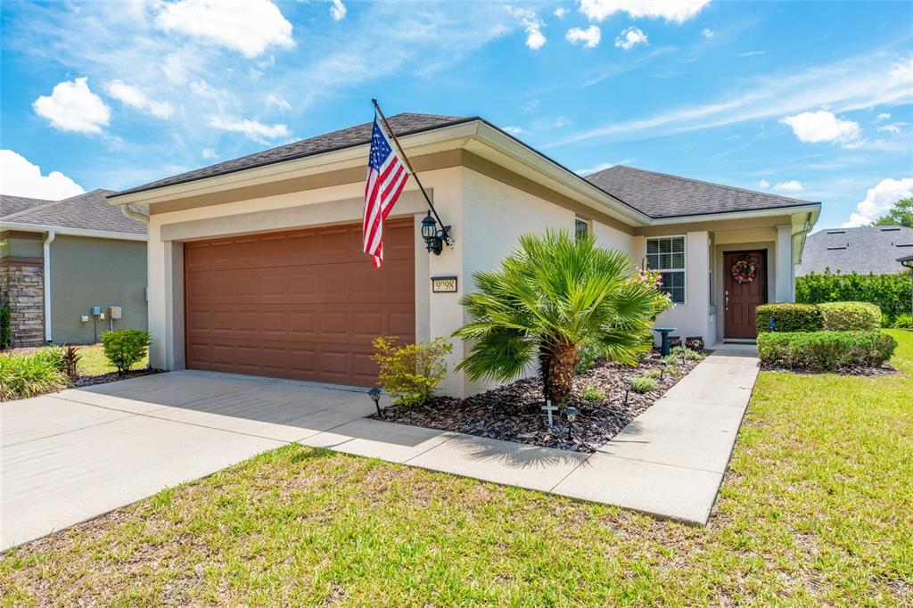 A single-story house with a brown garage door, a palm tree, and an American flag — 9098 SW 70TH LOOP, OCALA, FL