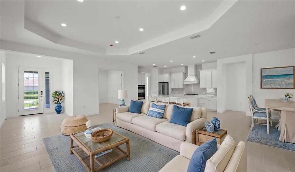 An open-concept living room and kitchen feature white cabinetry, tile flooring, and blue accents — 11540 VERANDAH PALM COURT, FORT MYERS, FL