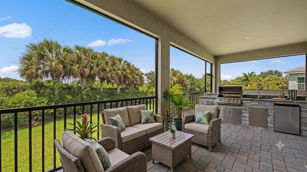 A screened-in patio features outdoor furniture, a built-in grill, a small refrigerator, and stone flooring — 11540 VERANDAH PALM COURT, FORT MYERS, FL