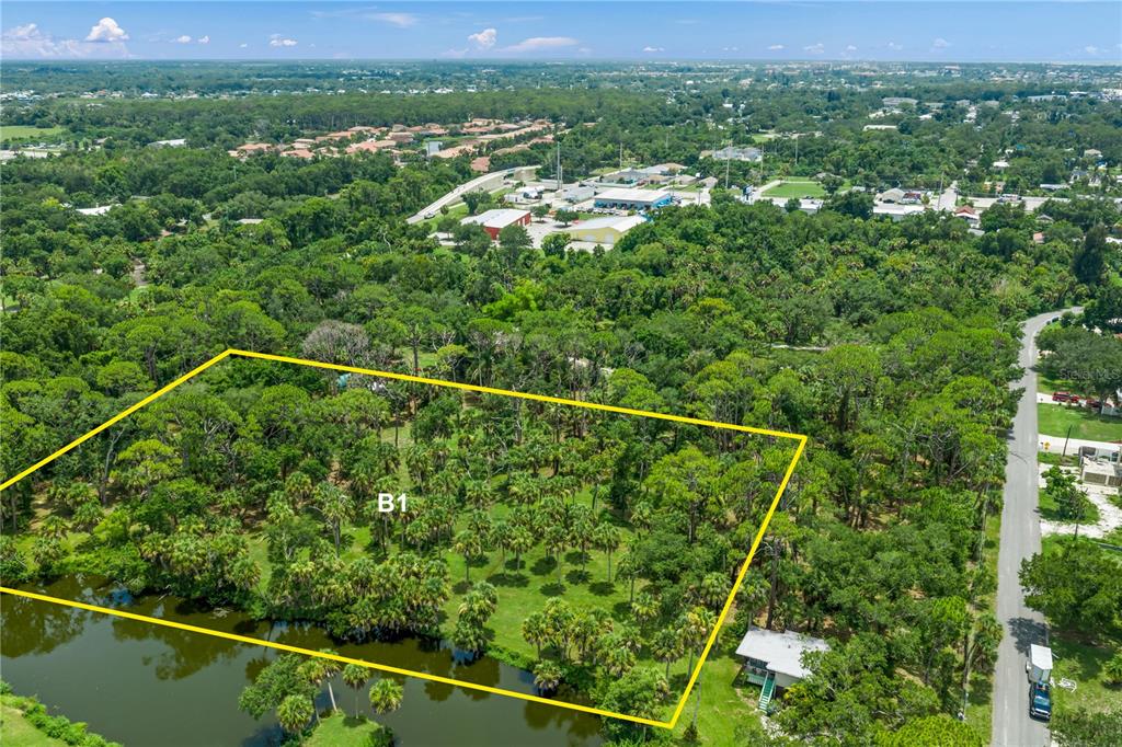 An aerial view shows a wooded lot marked with a yellow border near a pond — TWIN LAKES AVENUE UNIT B1, NOKOMIS, FL