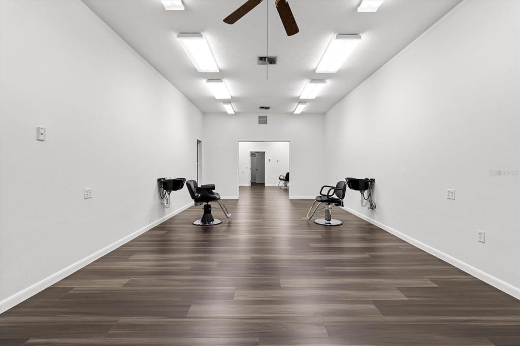 A long, minimalist salon room features two shampoo stations, dark flooring, and bright overhead lighting — 3438 N CITRUS AVENUE, CRYSTAL RIVER, FL