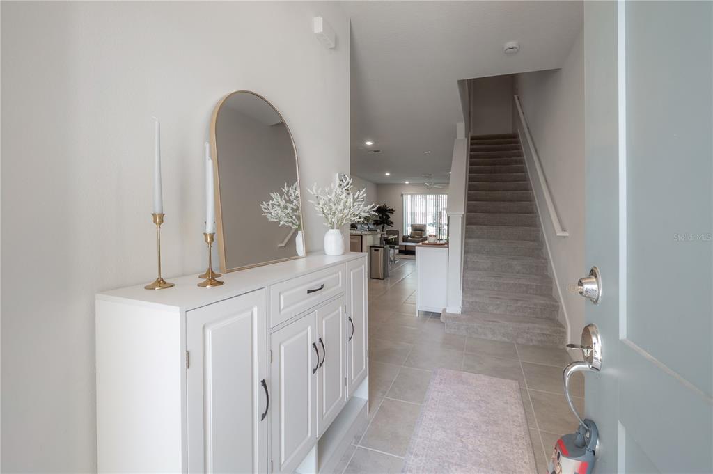 An entryway features a white console table, an arched mirror, and stairs leading to the second floor — 31428 AMBERVIEW BEND, WESLEY CHAPEL, FL