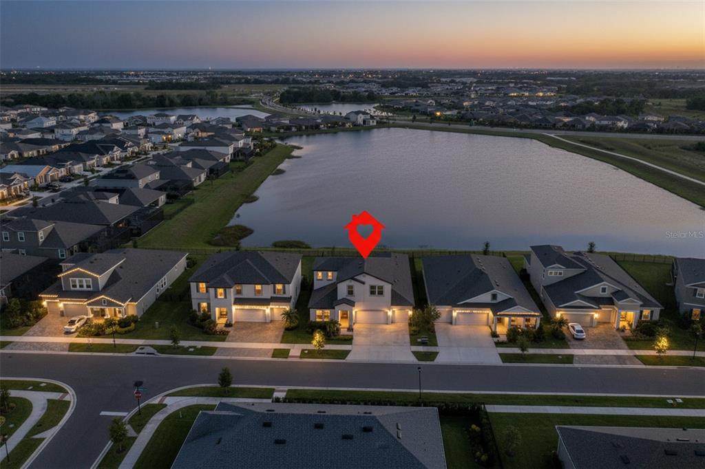 An aerial view shows a two-story house with a red marker overlooking a large lake — 5379 EVERLONG DRIVE, APOLLO BEACH, FL