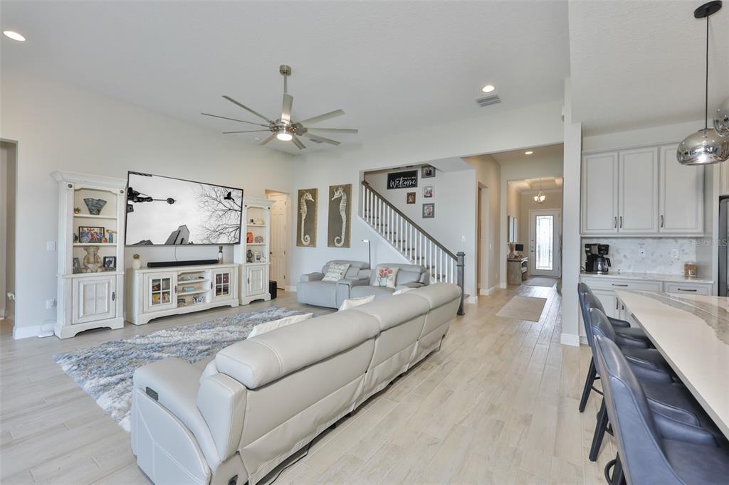 A living room features light wood floors, a large sectional sofa, and a wall-mounted television — 5379 EVERLONG DRIVE, APOLLO BEACH, FL