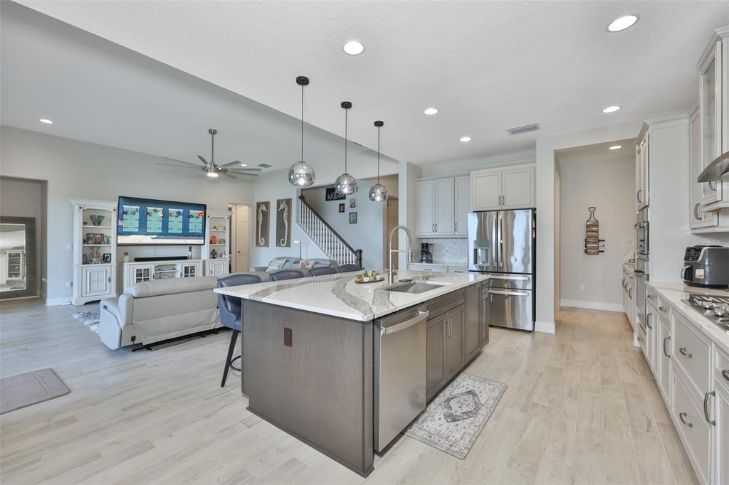A modern kitchen with a large dark island, white cabinets, and stainless steel appliances — 5379 EVERLONG DRIVE, APOLLO BEACH, FL