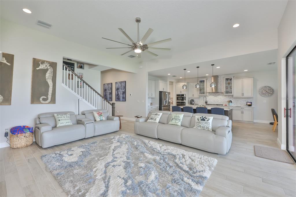 A living room with light gray sofas, a textured rug, and an open-concept kitchen beyond — 5379 EVERLONG DRIVE, APOLLO BEACH, FL