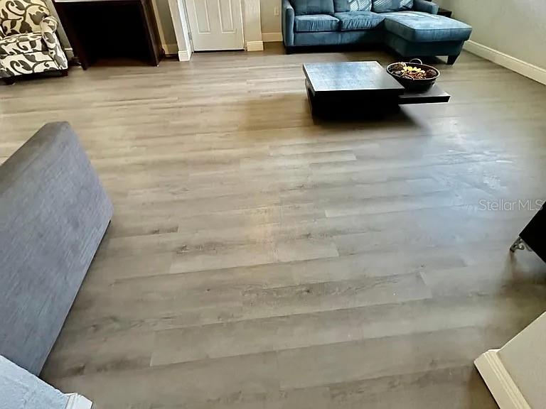 A living room features light-toned wood-look flooring, a blue sectional sofa, and a coffee table — 1605 36TH STREET NW, WINTER HAVEN, FL
