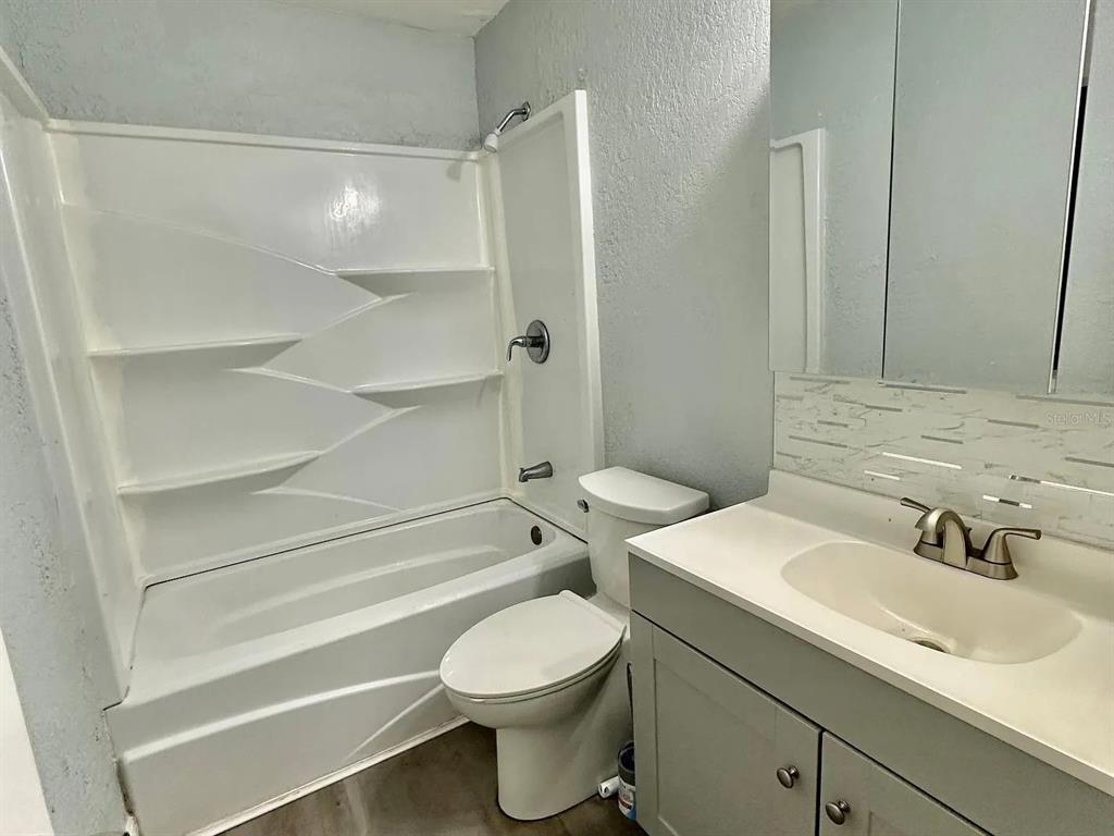 A bathroom features a white tub-shower combo, a toilet, and a vanity with a sink — 1605 36TH STREET NW, WINTER HAVEN, FL