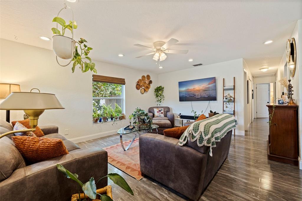 A living room features dark leather furniture, a glass coffee table, and wood-look flooring — 2940 47TH AVENUE S, ST PETERSBURG, FL