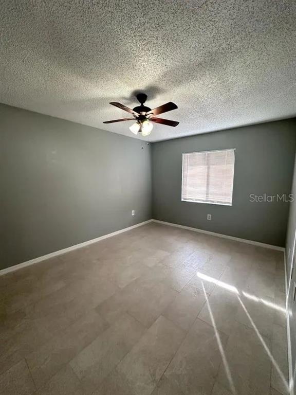 An empty bedroom features gray walls, tile flooring, a ceiling fan, and a window with blinds — 90 HIDDEN LAKE DRIVE UNIT 124, SANFORD, FL