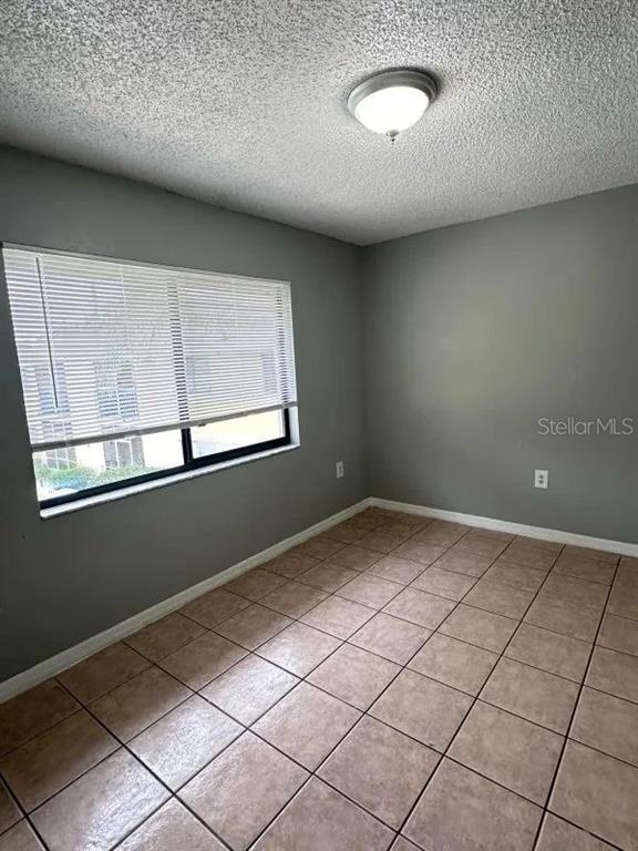 An empty room features gray walls, a tiled floor, and a window with white blinds — 90 HIDDEN LAKE DRIVE UNIT 124, SANFORD, FL