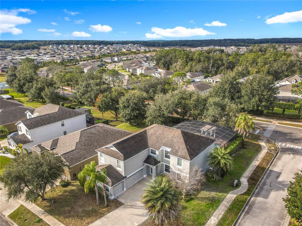 An aerial view shows a two-story suburban house with a screened pool and driveway — 4764 COPPOLA DRIVE, MOUNT DORA, FL