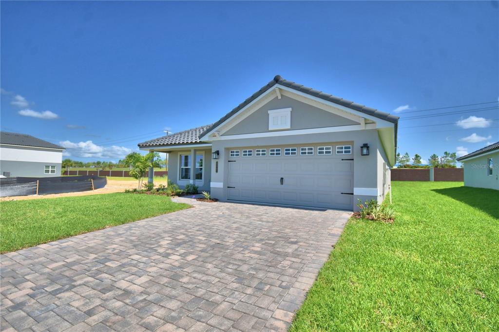 A single-story house with a gray stucco exterior, a tiled roof, and a paved driveway — 4467 JULIANA LAKE DRIVE, AUBURNDALE, FL