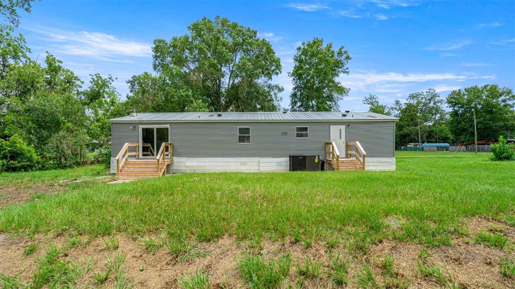 A gray manufactured home with two wooden entry decks sits on a grassy lot — 5363 ORANGE STREET, HAMPTON, FL