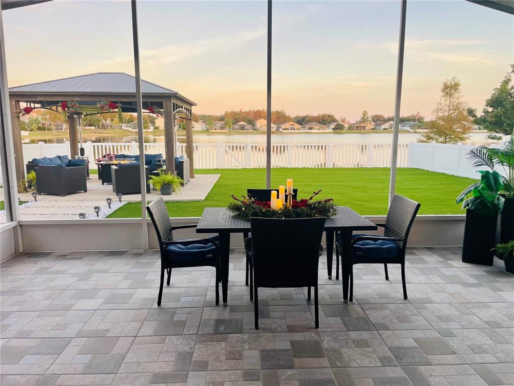 A screened-in patio features a dining set, tiled flooring, and a view of a lake — 2830 MUSKY MINT DRIVE, LAND O LAKES, FL