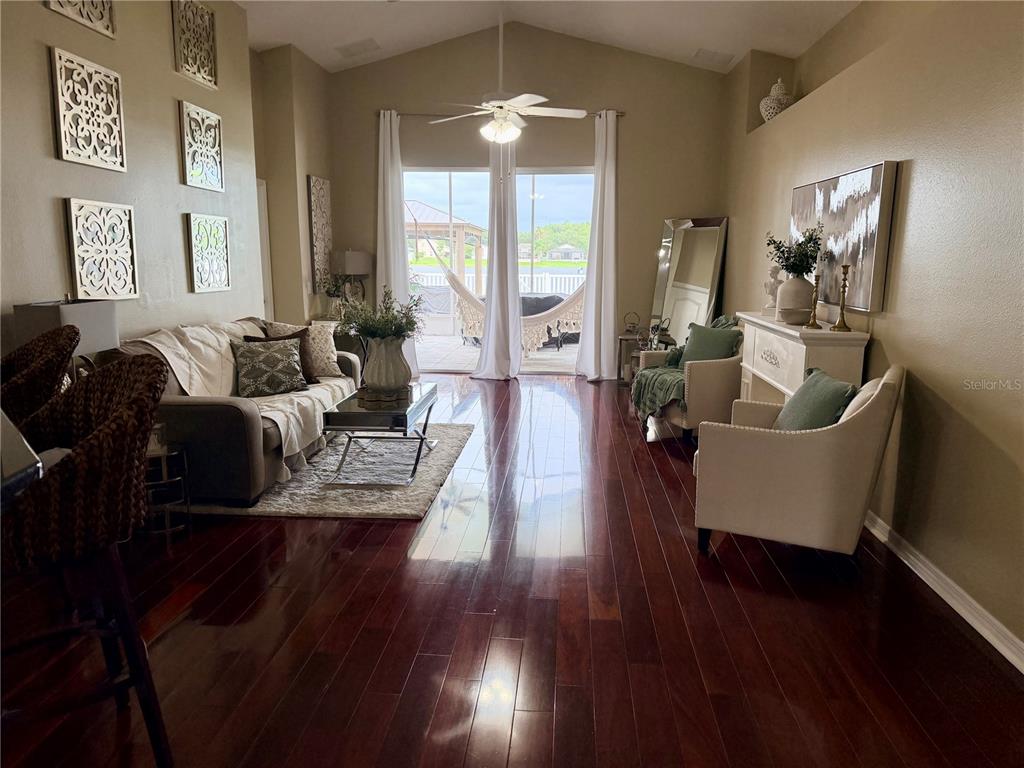 A living room features dark hardwood floors, a vaulted ceiling, and a sliding glass door — 2830 MUSKY MINT DRIVE, LAND O LAKES, FL