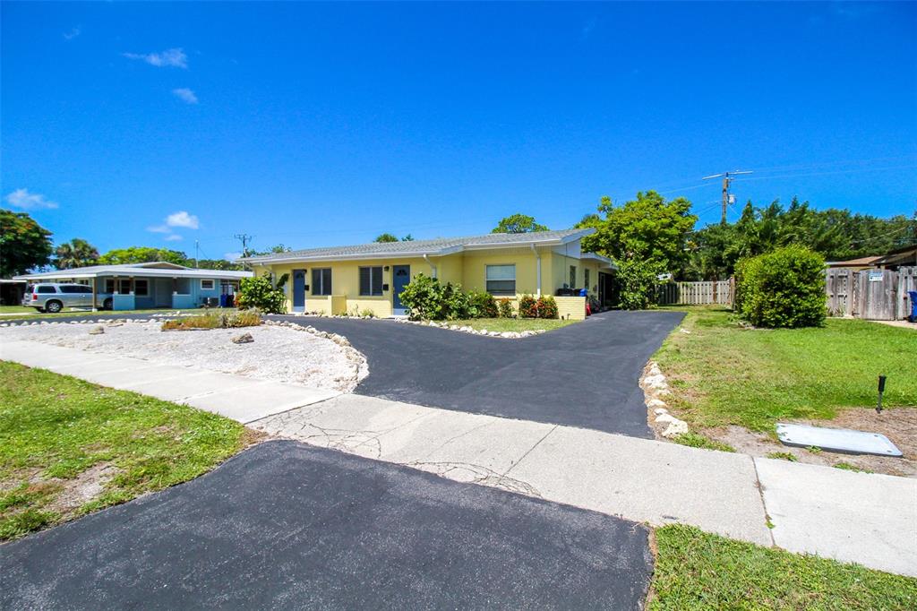 A yellow single-story duplex with a paved driveway and a gravel front yard — 606 HARBOR DRIVE S, VENICE, FL