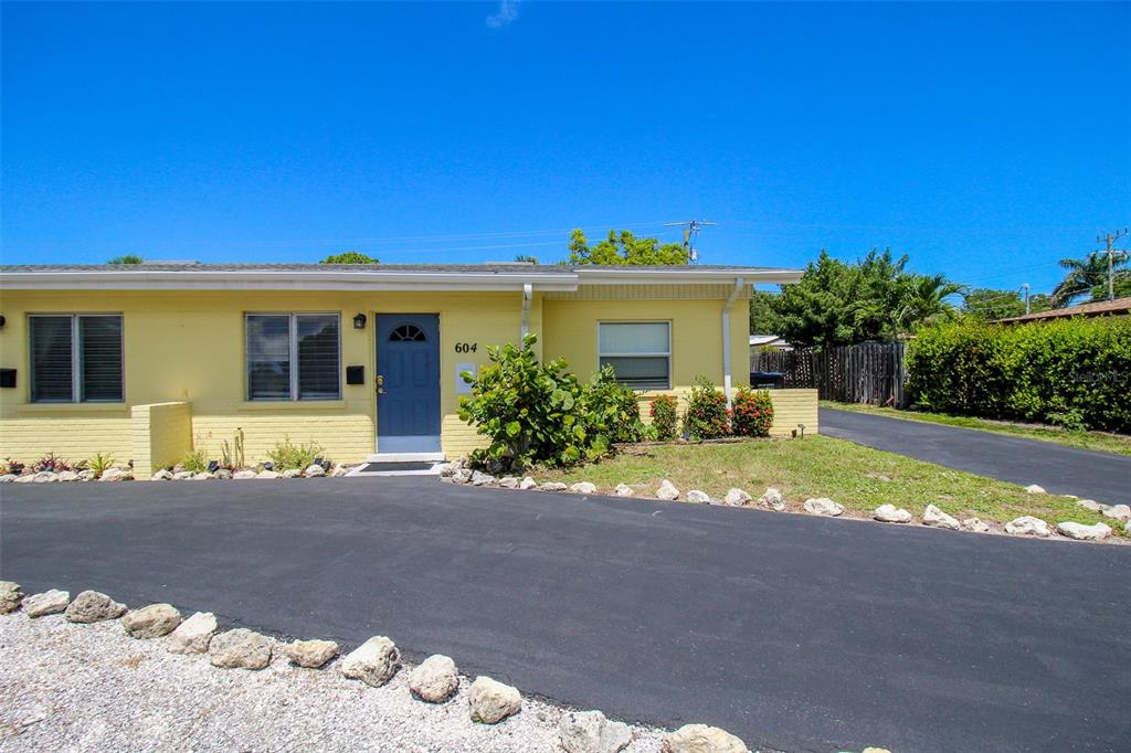 A yellow single-story building with a blue front door and a paved driveway — 606 HARBOR DRIVE S, VENICE, FL