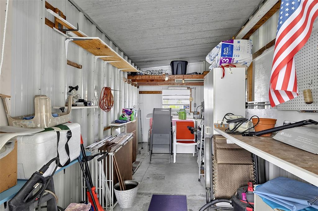 A cluttered storage shed features metal walls, wooden shelving, and a concrete floor — 248 LA ROSAS, NORTH PORT, FL