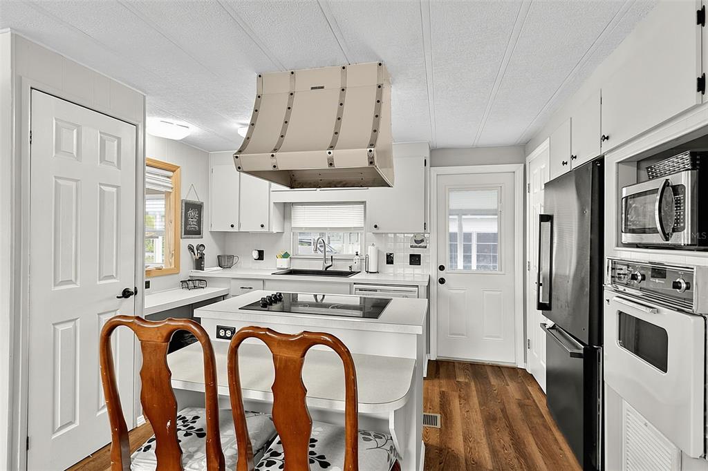 A kitchen features white cabinetry, a central island with a cooktop, and a range hood — 248 LA ROSAS, NORTH PORT, FL