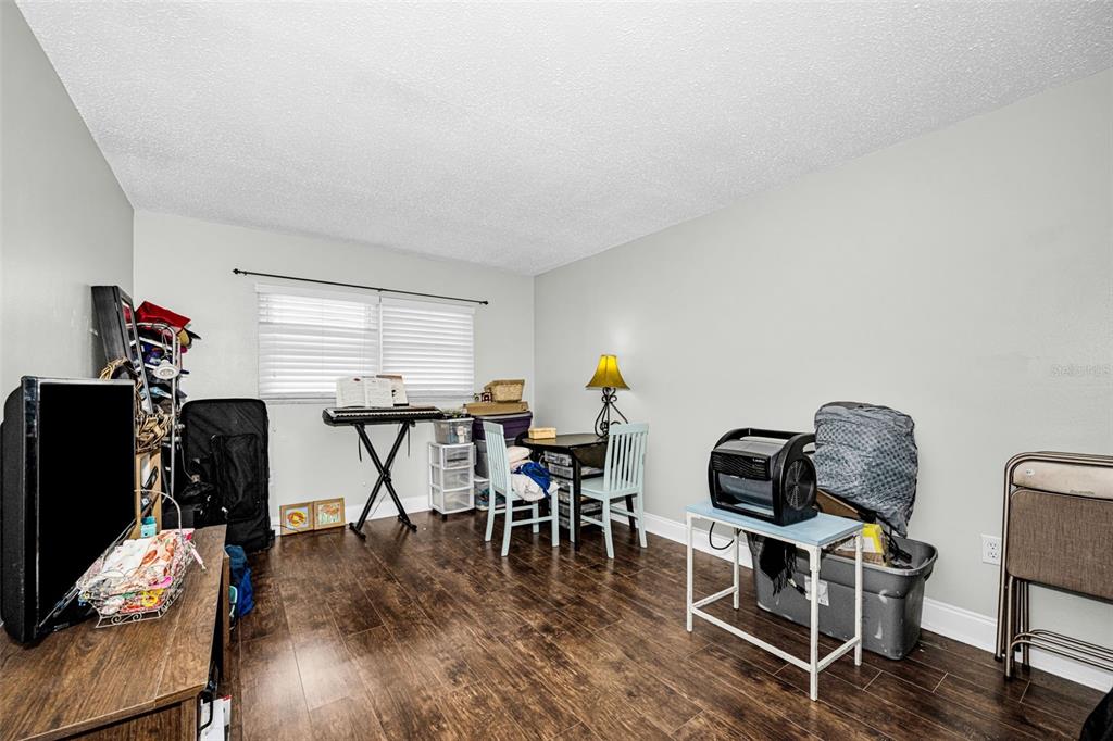 A room with wood-look flooring, a window with blinds, a small dining set, and miscellaneous items — 5060 76TH AVENUE N UNIT 401, PINELLAS PARK, FL