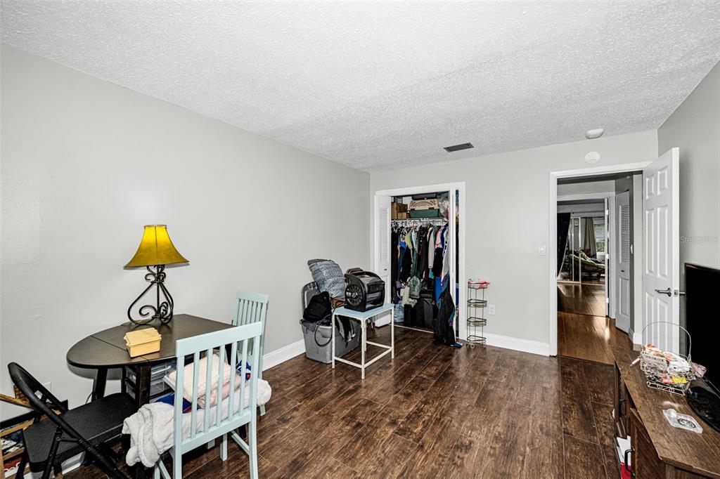A room with dark wood-look flooring, a small dining table, a closet, and a doorway — 5060 76TH AVENUE N UNIT 401, PINELLAS PARK, FL