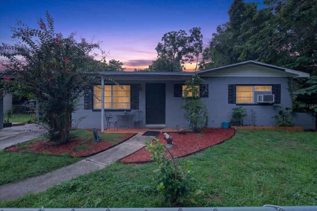 A single-story gray house with a front walkway, red mulch landscaping, and a dark door — 21385 LEHOUIER DRIVE, BROOKSVILLE, FL