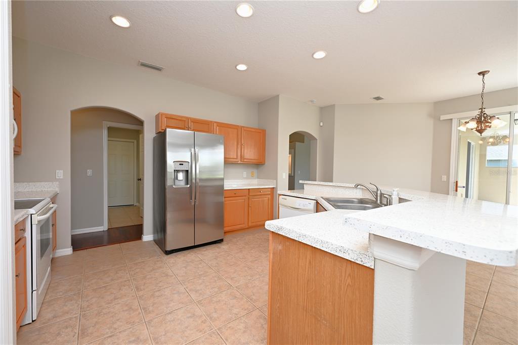 A kitchen with light wood cabinets, stainless steel appliances, and white countertops on tile flooring — 125 COSTA LOOP, AUBURNDALE, FL