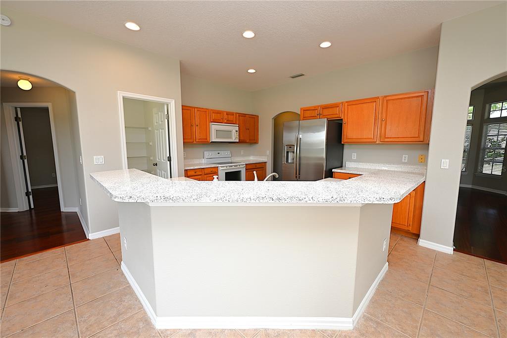 A kitchen with light-colored granite countertops, wood cabinets, and stainless steel appliances — 125 COSTA LOOP, AUBURNDALE, FL