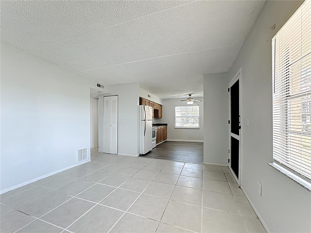 A living area with light tile flooring leads to a kitchen with wood cabinets — 694 MICHIGAN COURT UNIT 4, ST CLOUD, FL