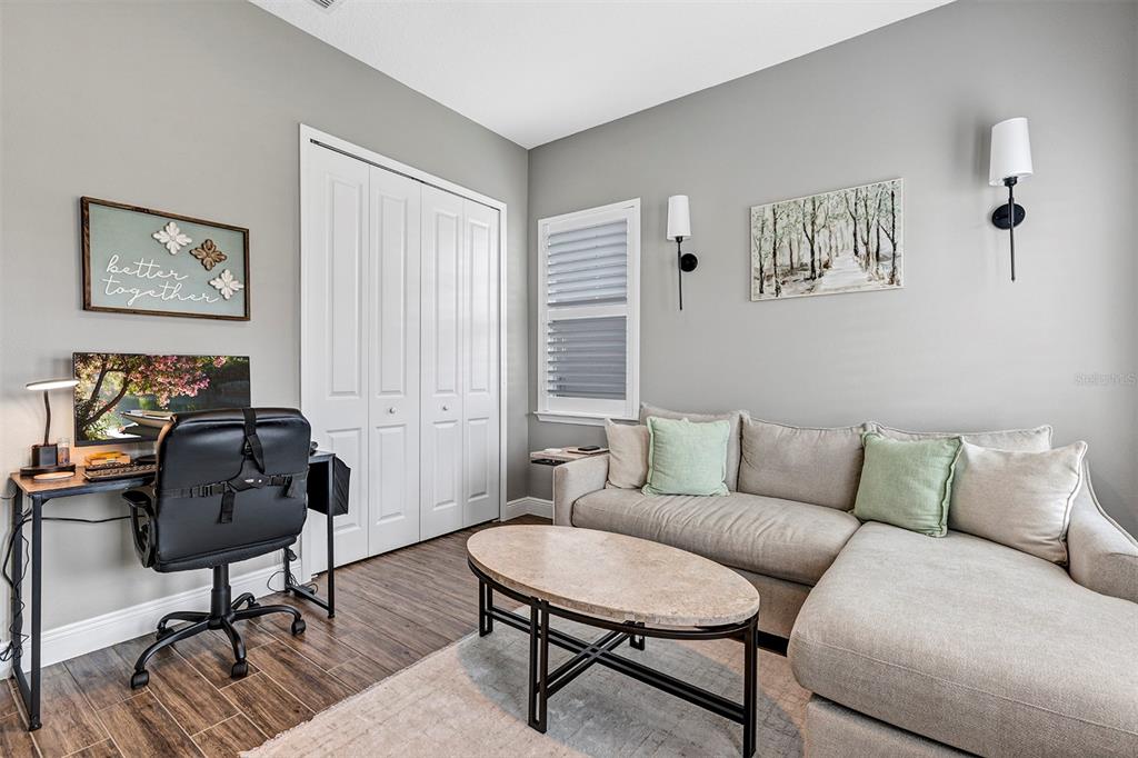 A home office and living area features a desk, sectional sofa, and wood-look flooring — 16136 VOLTERRA POINT, BELLA COLLINA, FL
