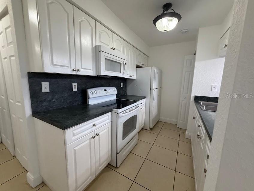 A kitchen features white cabinets, dark countertops, white appliances, and light-colored floor tiles — 2718 RIO GRANDE TRAIL UNIT 2718, KISSIMMEE, FL