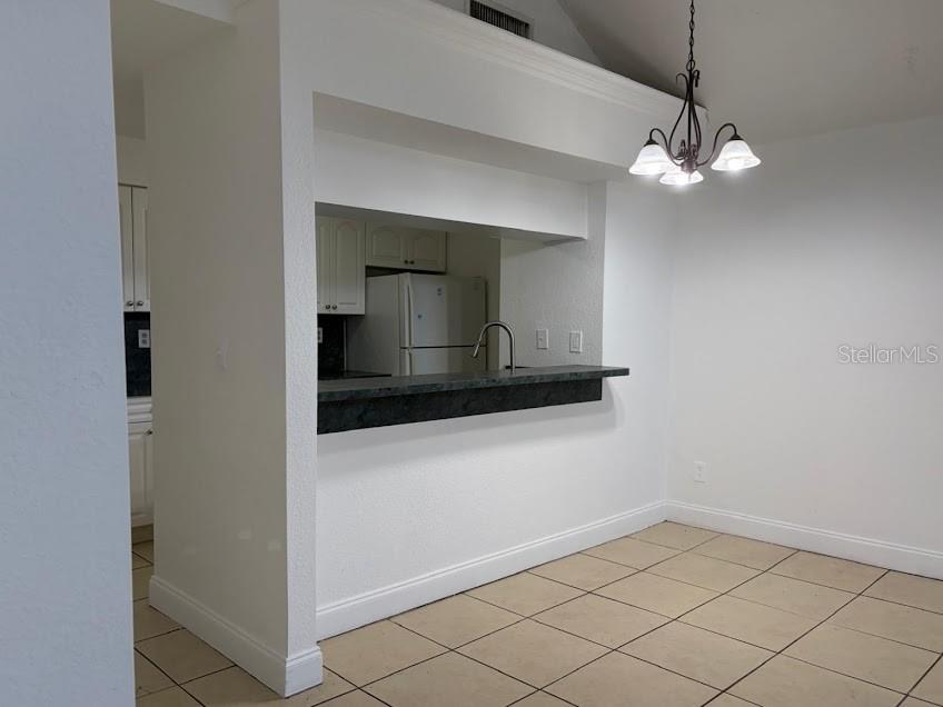 A dining area with tile flooring features a pass-through window overlooking a kitchen — 2718 RIO GRANDE TRAIL UNIT 2718, KISSIMMEE, FL