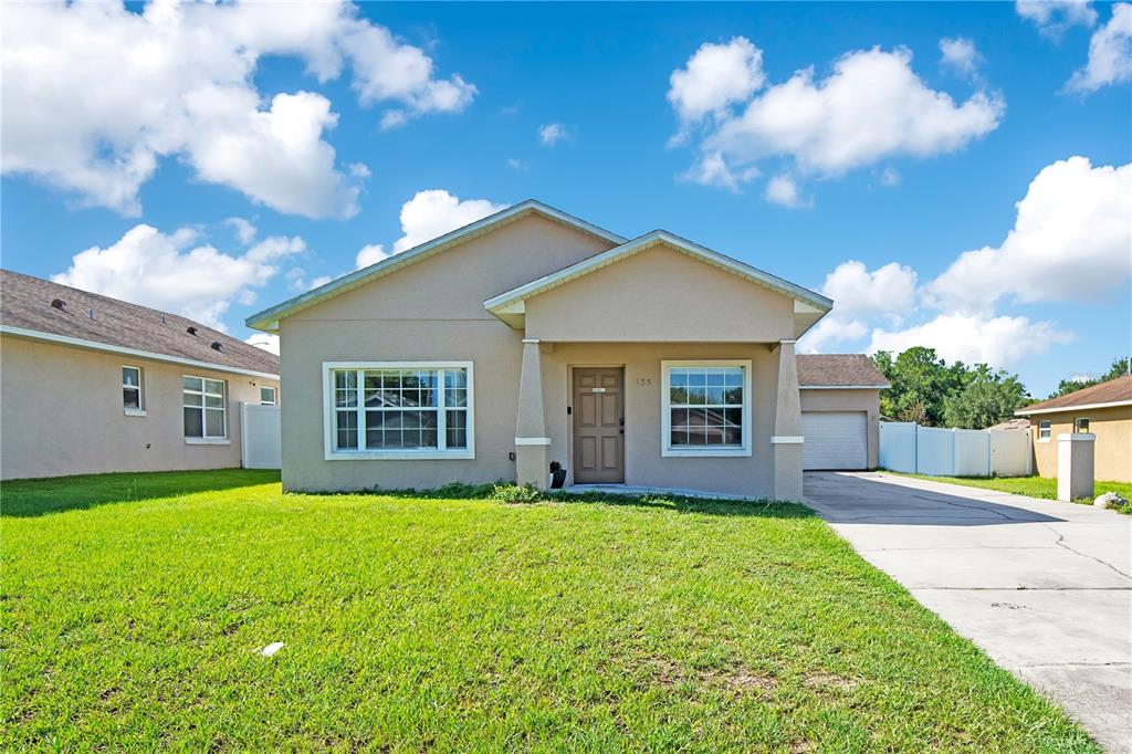 A single-story house with a beige exterior, a front porch, and a driveway with a car — 135 PARKER COVE COURT, OCOEE, FL