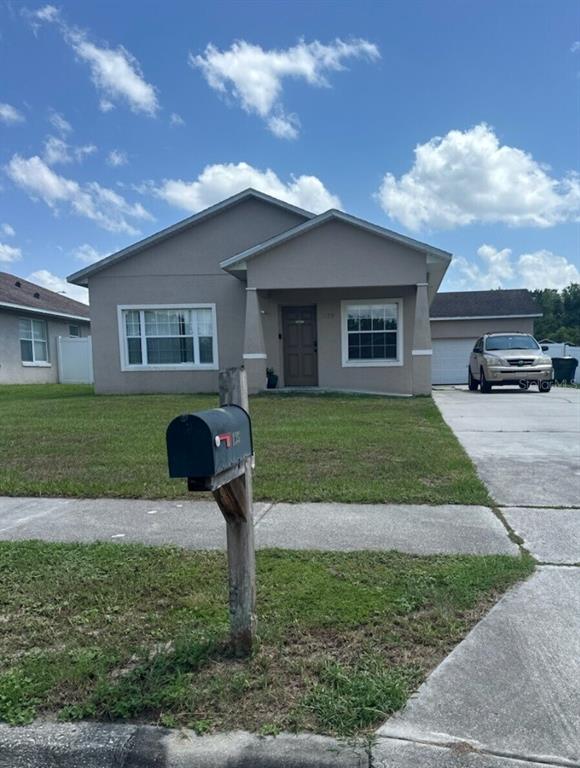 A single-story house with a beige exterior, a front porch, and a driveway with a car — 135 PARKER COVE COURT, OCOEE, FL