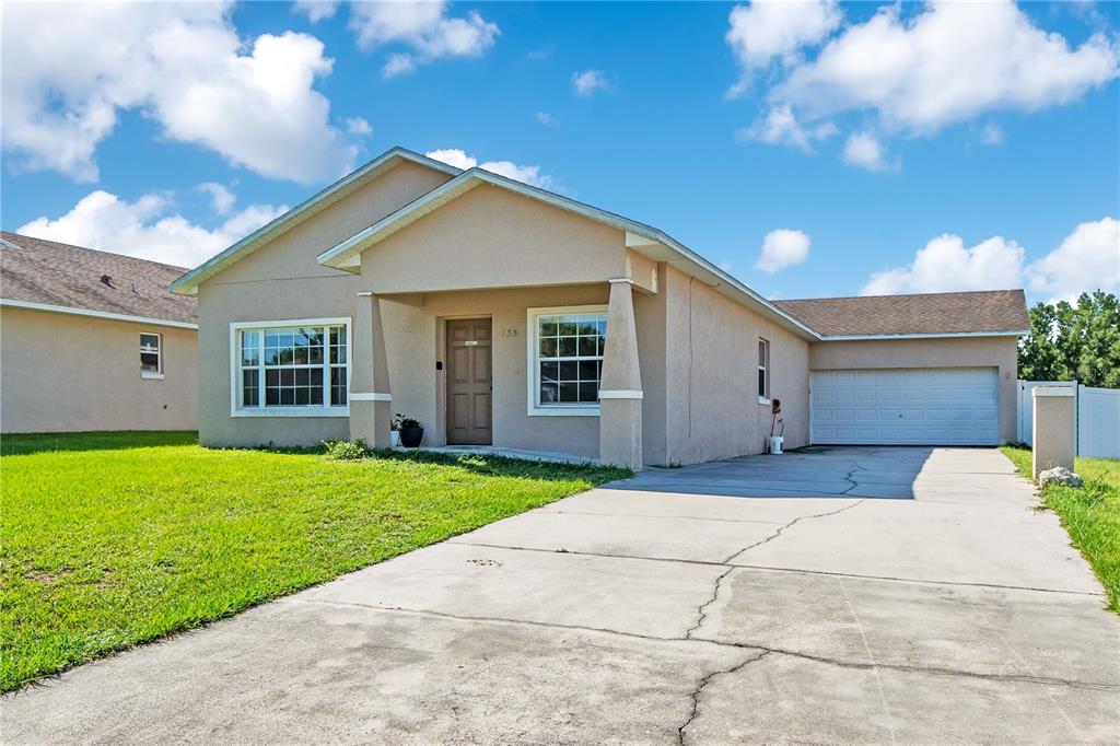 A single-story tan house with a concrete driveway and an attached two-car garage — 135 PARKER COVE COURT, OCOEE, FL