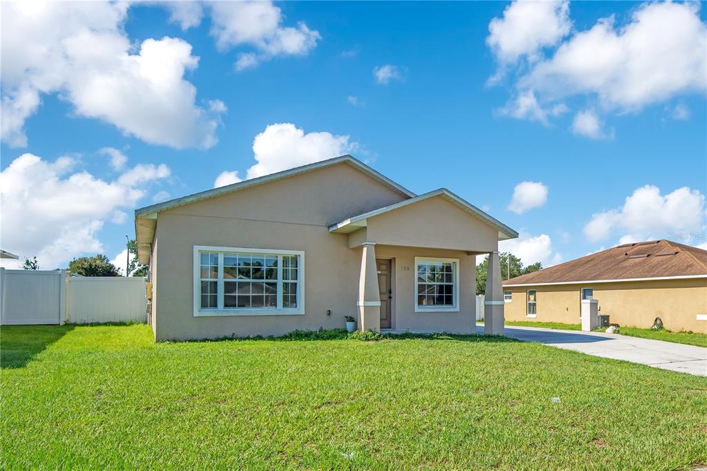 A single-story tan house with a covered front porch and a large front lawn — 135 PARKER COVE COURT, OCOEE, FL