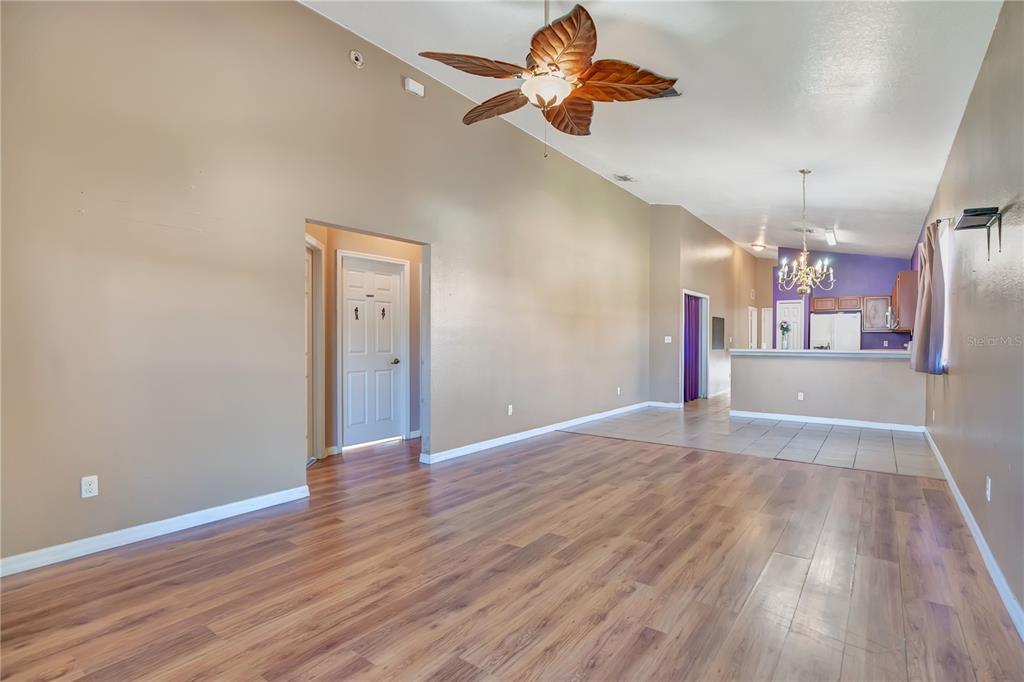 A living room with wood-look flooring, a ceiling fan, and an open kitchen beyond — 135 PARKER COVE COURT, OCOEE, FL
