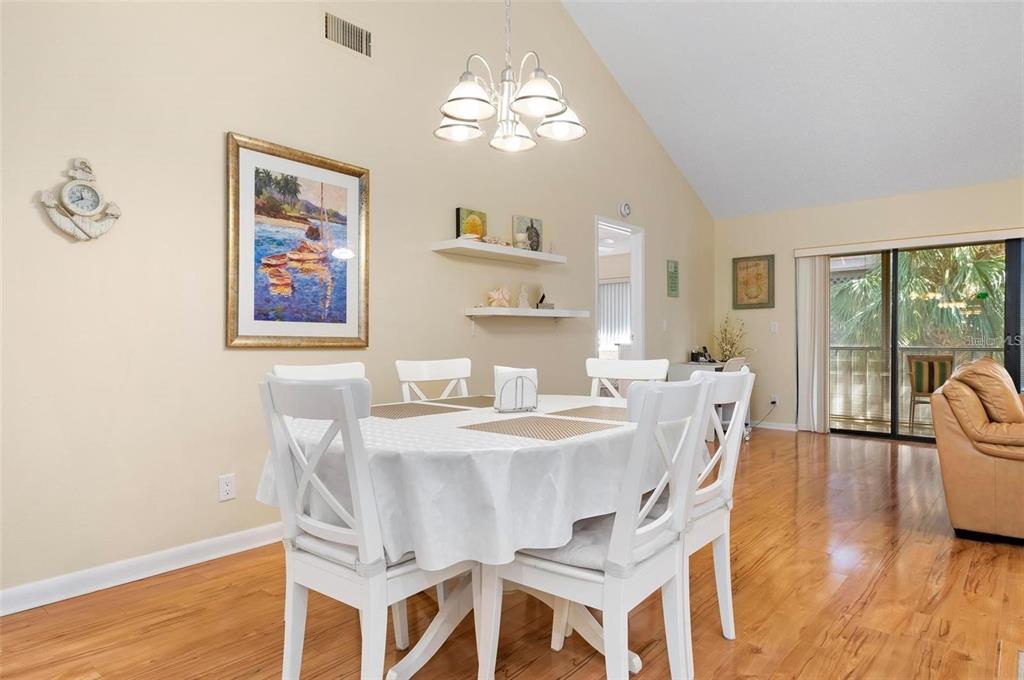 A dining room with a white table, four chairs, a chandelier, and hardwood flooring — 1707 PELICAN COVE ROAD UNIT 451, SARASOTA, FL