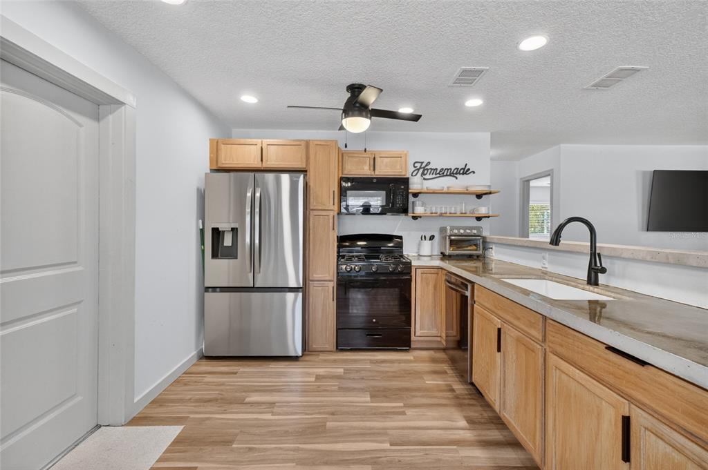 A kitchen features wood cabinets, stainless steel appliances, a black stove, and a concrete countertop — 529 E GOTTSCHE AVENUE, EUSTIS, FL