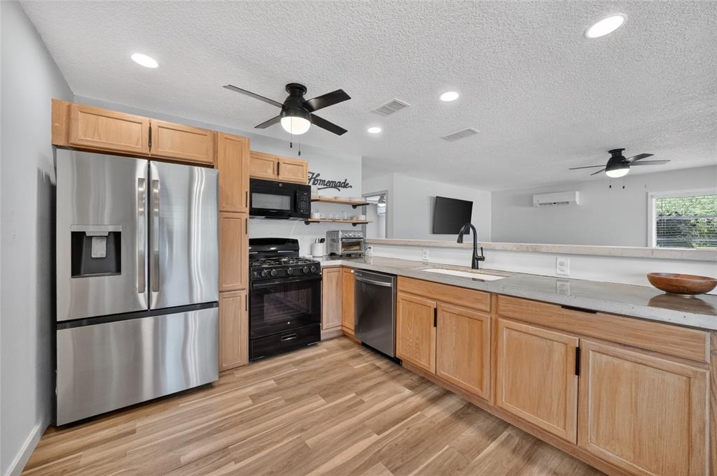 A kitchen features light wood cabinets, stainless steel appliances, and a concrete-style countertop — 529 E GOTTSCHE AVENUE, EUSTIS, FL