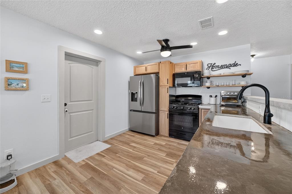 A kitchen features stainless steel appliances, light wood cabinets, and a dark concrete countertop — 529 E GOTTSCHE AVENUE, EUSTIS, FL