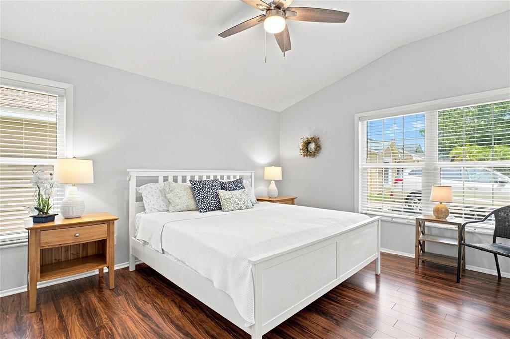 A bedroom features a white bed, wooden side tables, a ceiling fan, and hardwood floors — 864 FRANKLIN CIRCLE, PALM HARBOR, FL