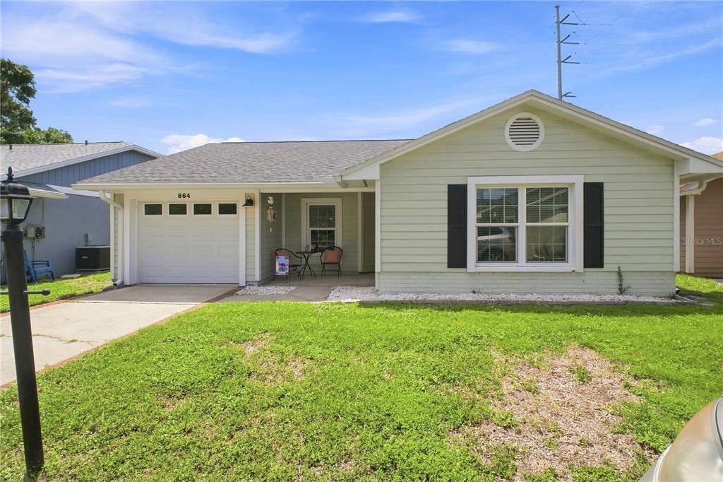 A single-story house with light green siding, a one-car garage, and a front porch — 864 FRANKLIN CIRCLE, PALM HARBOR, FL