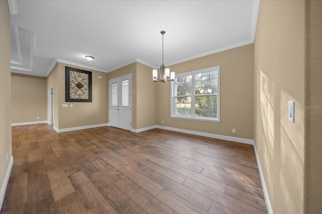 A dining room features wood-look flooring, tan walls, a chandelier, and a double-door entrance — 2087 N ANNAPOLIS AVENUE, HERNANDO, FL